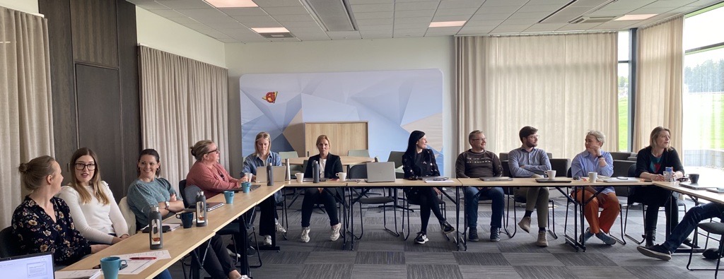 Anställda vid AJ produkter sitter vid ett långt bord i konferensum