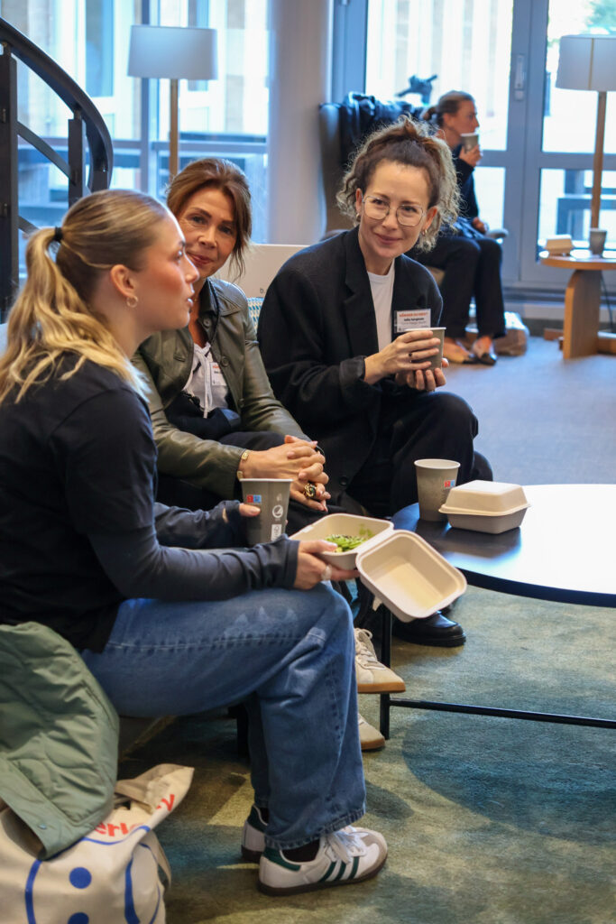 Tre kvinnor som sitter och konverserar och dricker kaffe.