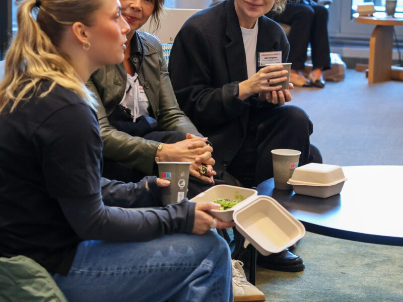 Tre kvinnor som sitter och konverserar och dricker kaffe.