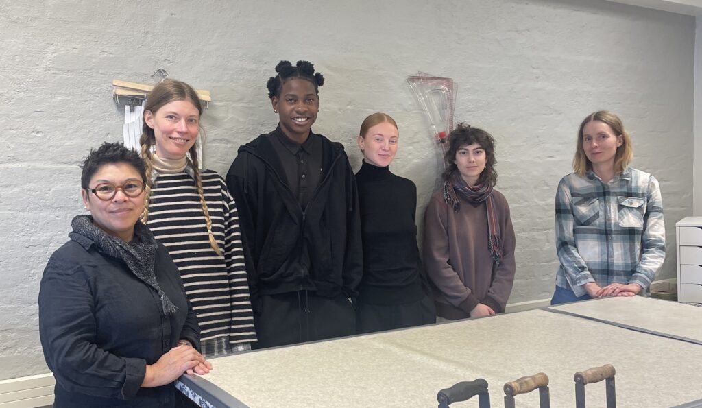 Fem personer står på rad bakom ett bord