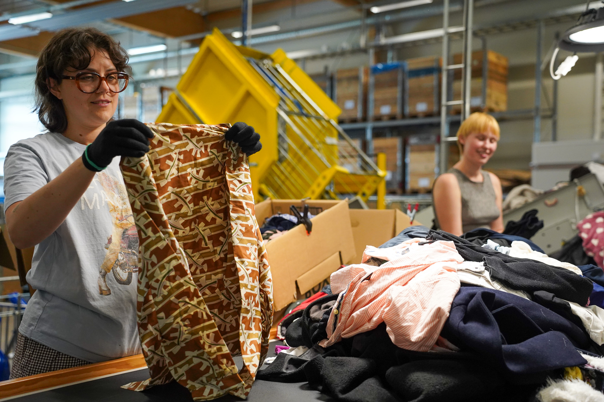 bild på två personer som arbetar vid ett löpande band och granskar textil