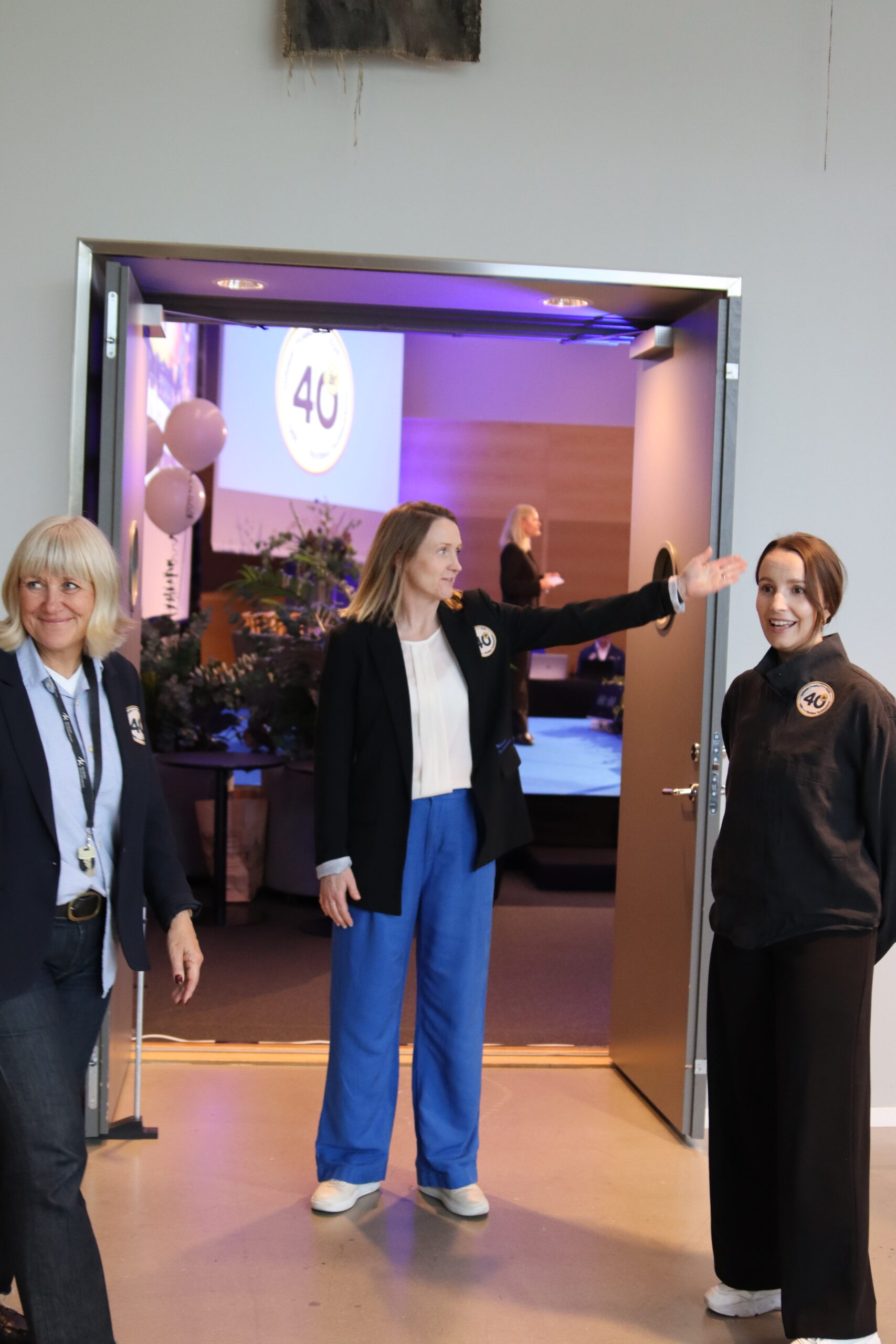 kvinnor som står värdar vid en dörr med 40-årsdekal på kläderna